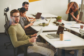 Calm male office worker posing at his workplace