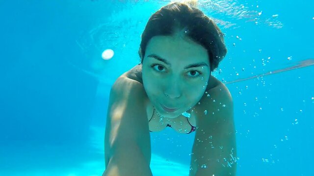 Portrait of young woman diving in pool. Girl swimming under water and filming himself. Female tourist enjoying resting on resort at summertime. Underwater footage. Summer vacation or travel concept