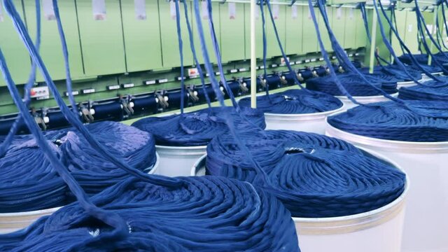Piles of blue yarn are getting mechanically unwound