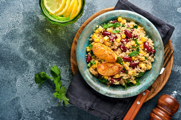 Mexican black bean corn quinoa salad with caramelized lemon in old vintage clay bowl on a dark gray concrete background. Traditional Mexican cuisine dish. Top view, mock up.