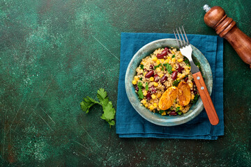 Mexican black bean corn quinoa salad with caramelized lemon in old vintage clay bowl on a dark green concrete background. Traditional Mexican cuisine dish. Top view, mock up.