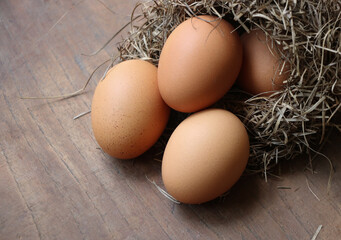 Fresh poultry eggs are uncooked near the nest top view on the wooden background