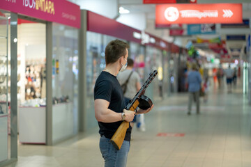 A man in a mask in a shopping center stands with a weapon