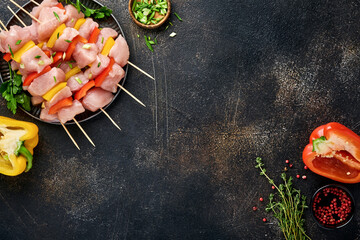 Raw shish kebab on wooden board, spices, herbs and vegetables on dark grey background. Barbecue Raw...
