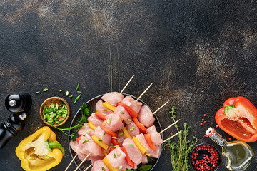 Raw shish kebab on wooden board, spices, herbs and vegetables on dark grey background. Barbecue Raw...