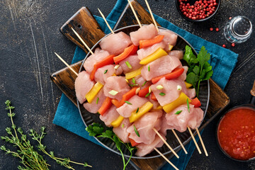 Raw shish kebab on wooden board, spices, herbs and vegetables on dark grey background. Barbecue Raw...