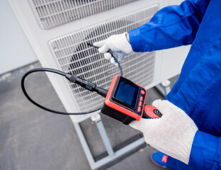 the technician uses a digital camera to check the clogging of the heat exchanger