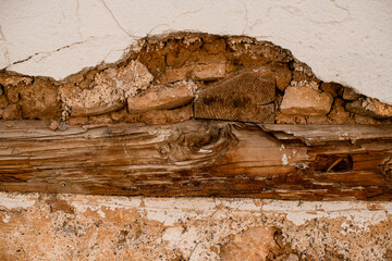 close-up of the wall with wooden beam and peeling plaster