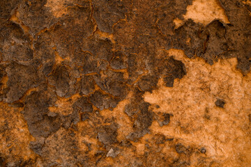 old building wall with weathered and peeling red paint cracks on plaster.