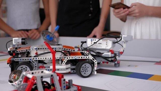 Children control cars robots assembled from a constructor in a robotics school