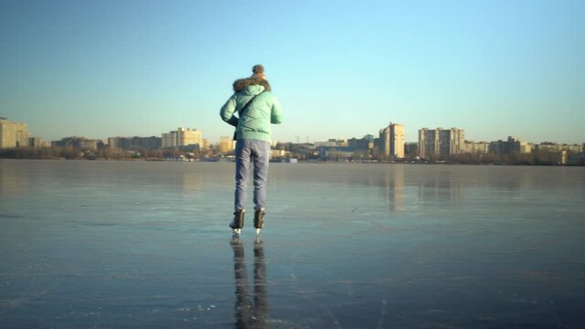 Adult caucasian woman in blue jacket and light jeans skates on ice