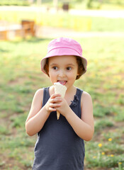 Cute toddler girl in a hat eating ice cream