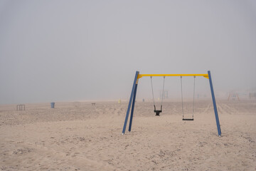The beach of the Baltic Sea in Ventspils where there are various swings and other attractions is in thick fog