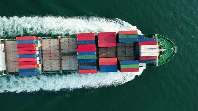 Aerial zoom out view of cargo maritime ship with contrail in the ocean ship carrying container and running for export  concept technology freight shipping by ship smart service