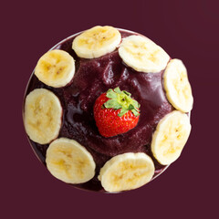 Açai, Brazilian frozen açai berry ice cream bowl with bananas slices and strawberry. Top view. Isolated on purple background