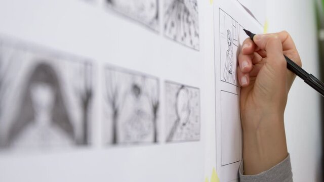 A designer draws a storyboard for an animated film comic strip. Scene sketches for the cartoon. 4K.