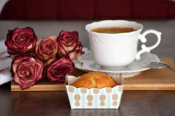 Mini marble cake or pound cake in a paper baking mold or tray in front of a white coffee cup and red dried roses