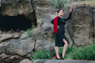 Low angle view of gorgeous and attractive woman standing in the middle of huge cliffs and touching them
