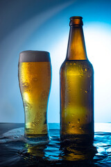 bottle of beer with a glass of foamy beer on a blue background, on the water