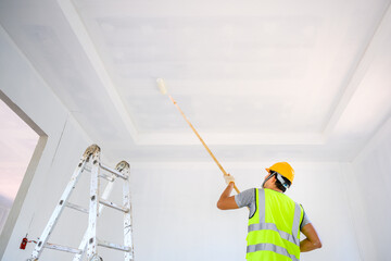 Young Asian male construction worker Work as a house painter Painting the ceiling inside the house...