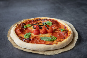 Concept food. Beautiful epperoni pizza with tomatoes on a dark background.