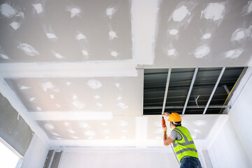 Young male construction workers wearing uniforms Installing gypsum ceiling inside the house and...