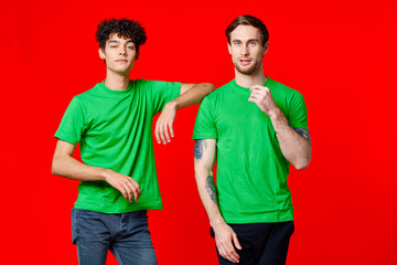 Two cheerful friends in green t-shirts joy of communication red background