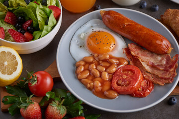 Delicious breakfast with fresh croissants, bacon, beans, sausage with fried egg, tomato and coffee served, milk, orange juice. strawberry, butterhead, blackberry salad. full american healthy breakfast