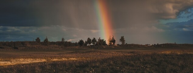 Landscape with sky after rain at sunset with rainbow