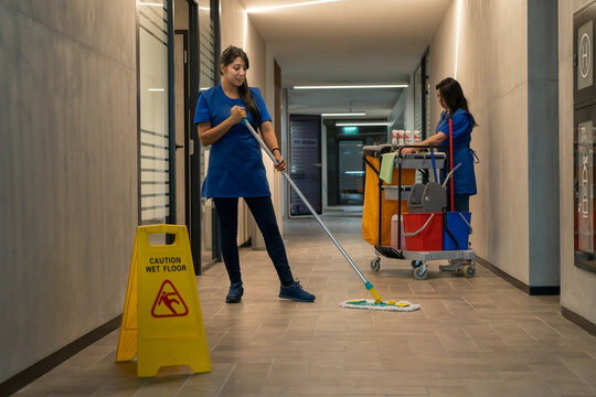 Cleaner mops the floor while the other prepares the detergents