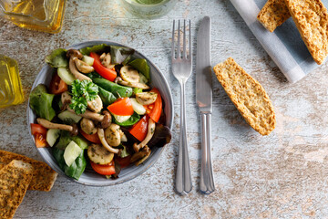 mushroom salad in a bowl. Summer meal a salad with himeji, oyster fungus, white Paris mushrooms mixed with young lettuce, tomatoes and cucumber.