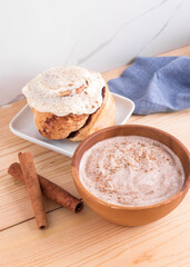 Cinnamon roll, cinnamon sticks, and cinnamon yogurt on wooden surface