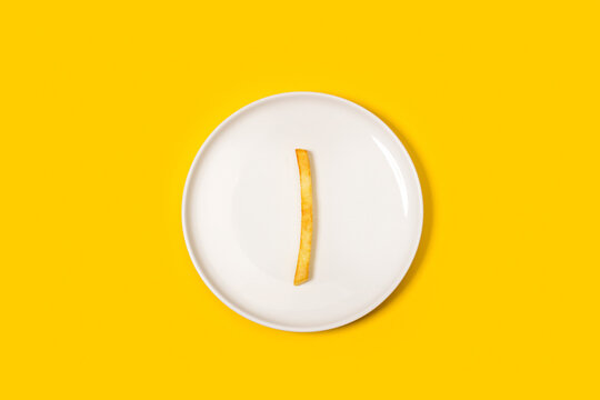 Una patata frita sobre un plato redondo blanco sobre un fondo amarillo liso y aislado. Vista superior. Copy space