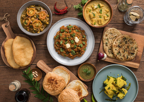 Flatlay of indian food: punjabi chole, pav bhaji, shahi paneer, and dhokla