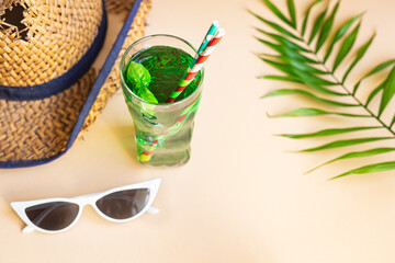 green lemonade tarragon or basil beverage summer background refreshing ice drink straw hat, sunglasses relax positive mood vacation top view