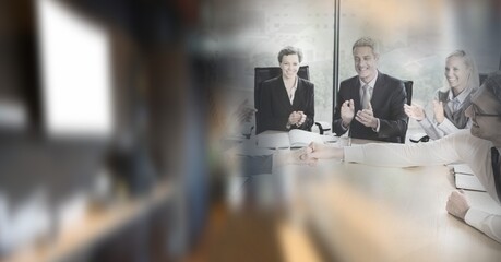 Happy male and female business people shaking hands and clapping in office with motion blur