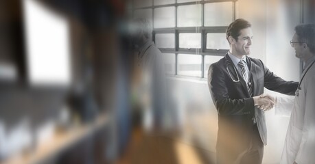 Composition of two smiling male doctors shaking hands in office with double exposure