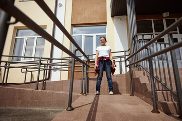 Fototapeta premium Young woman with skateboard on the background of a yellow building