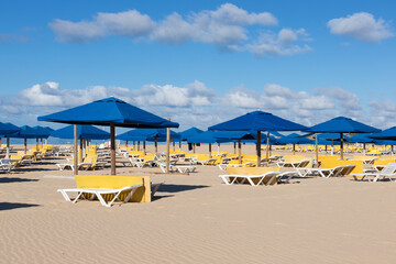 Yellow beach chairs and blue umbrellas. Praia da Rocha, Portimão, Algarve, Portugal