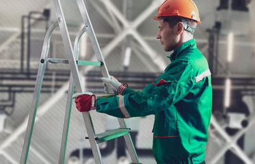 male worker on construction site holding and carrying the ladder