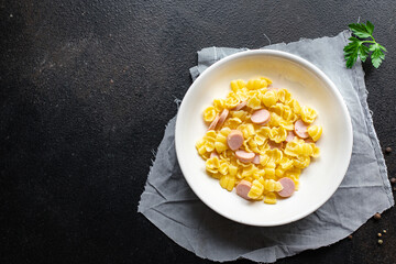 pasta Conchiglie sausages, cucumber salad vegetables kids menu on the table healthy food children's menu meal snack copy space food background rustic. top view