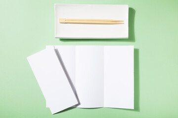 Mockup asian cuisine restaurant menu or brochure, sushi plate and food sticks on green background
