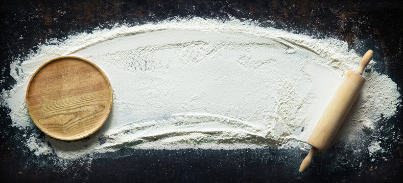 Abstract Baking Background With The Rolling Pin And Flour On Dark Table