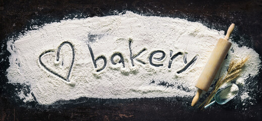 Abstract baking background with the rolling pin and flour on dark table