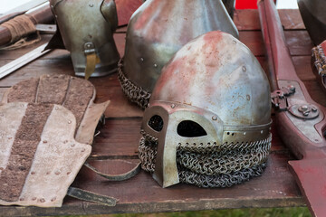 an old knight's helmet with scratches and dents lies on a wooden table.