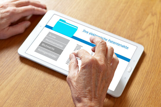 Hands of an old woman touching the screen of a tablet computer, translation of german text: your personal patient record.