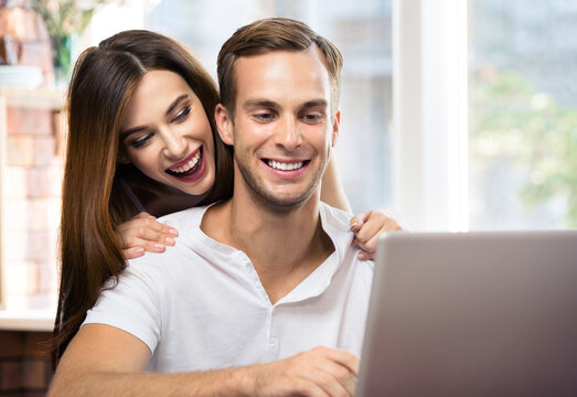 Happy excited smiling couple using laptop at home. Internet, shopping, online store, love, relationship concept - man and woman with domestic computer. Square composition picture.