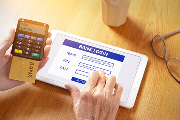 Hands of senior woman with a tablet computer and a confirmation code generator for online log in to the bank account.
