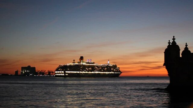 Big cruise ship sailing on the sunset towards Belem Tower in Lisbon, Portugal