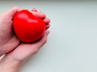 A red heart in the hands of a person. Copy space. Isolated on white background.